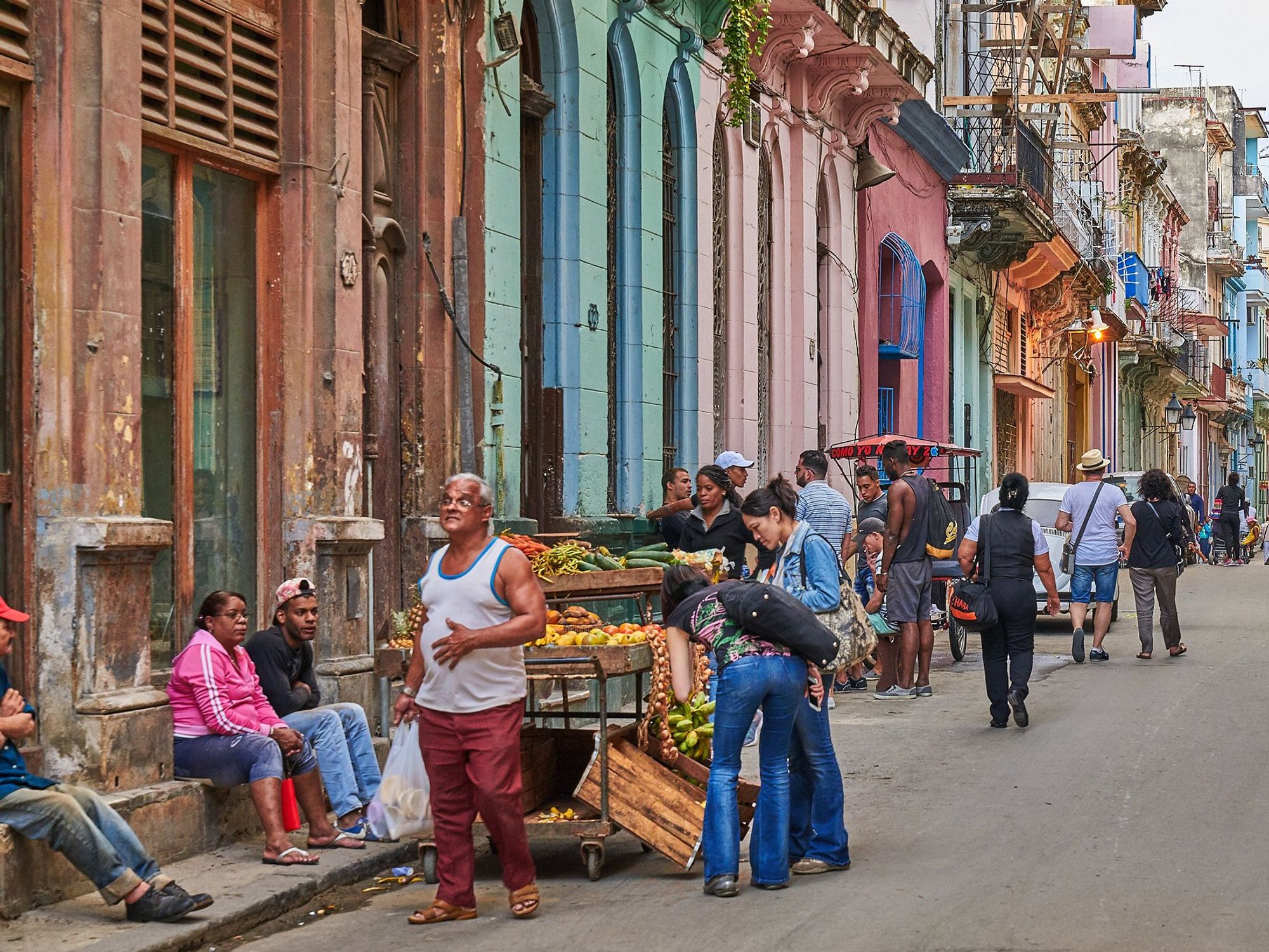 Photo of a street in Havana, Cuba with people stopping to buy fruits and vegetables