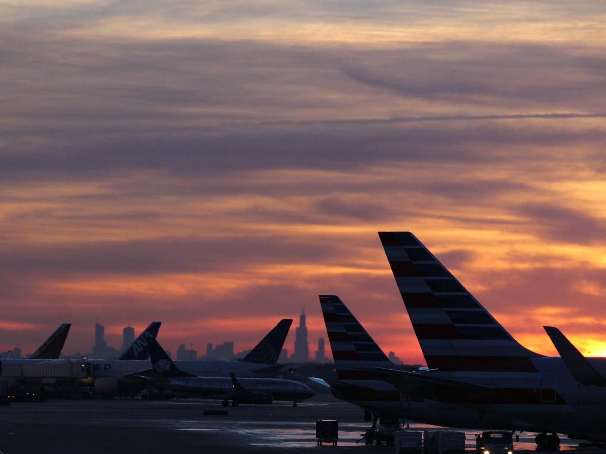 Photo of a sunset over Chicago's O'Hare airport with backlit plane tails