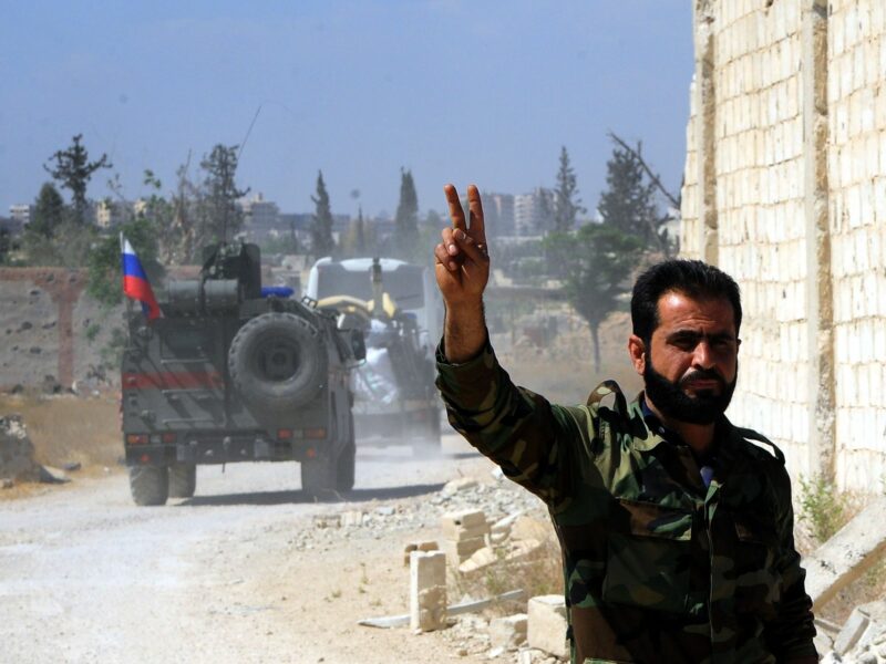 Photo of a Syrian soldier flashing the victory sign as Russian military vehicles enter the Douma district in the eastern countryside of the capital Damascus of Syria