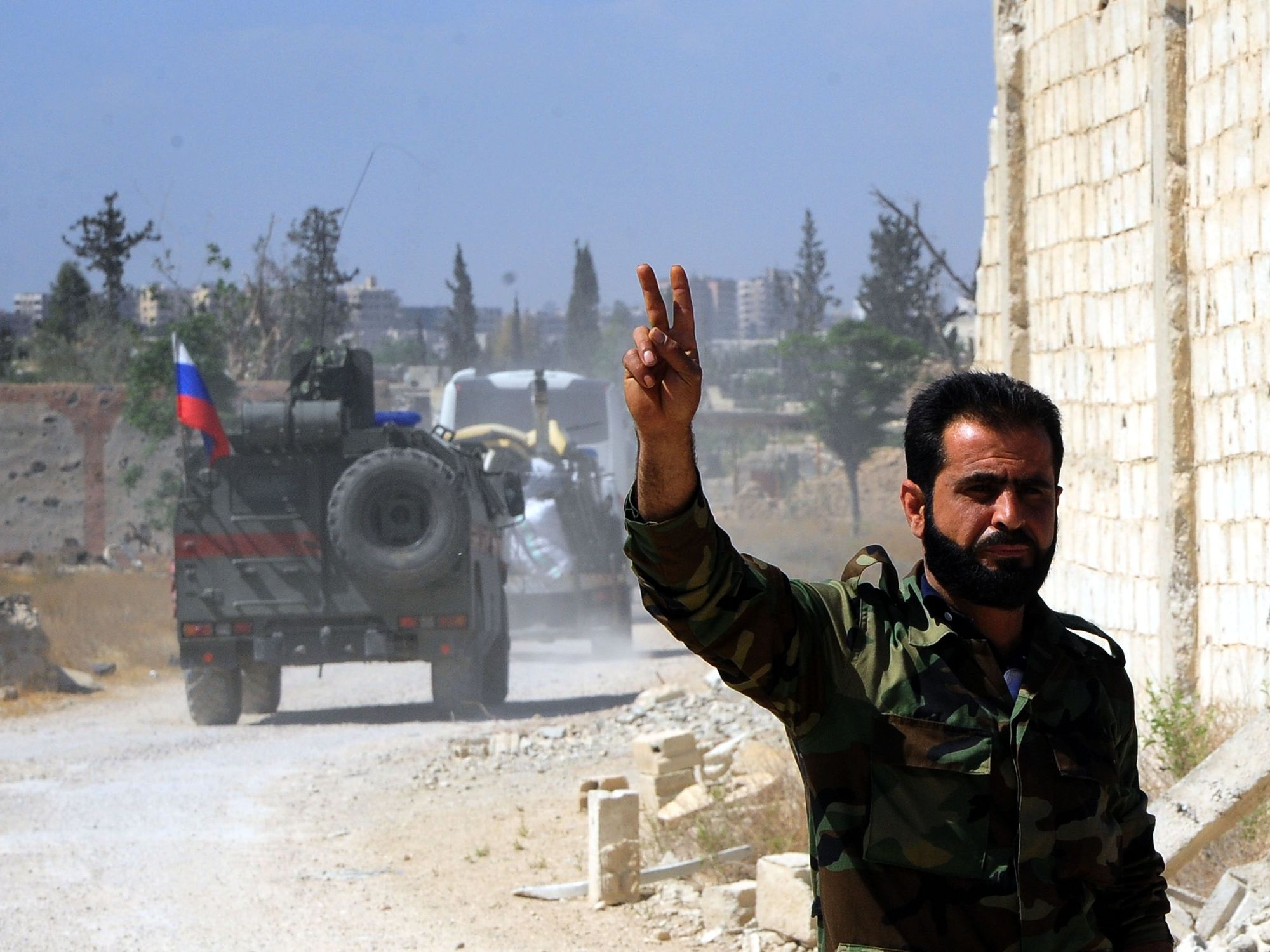Photo of a Syrian soldier flashing the victory sign as Russian military vehicles enter the Douma district in the eastern countryside of the capital Damascus of Syria