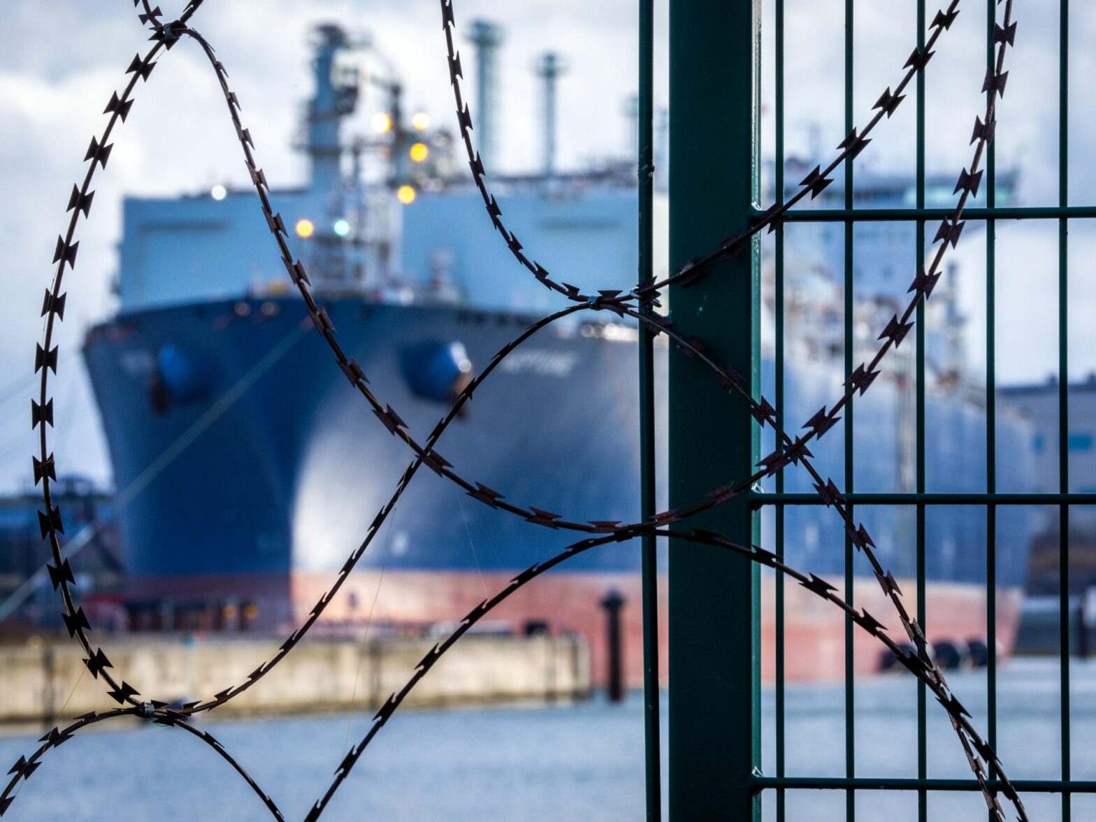 photo of a tanker ship behind barbed wire