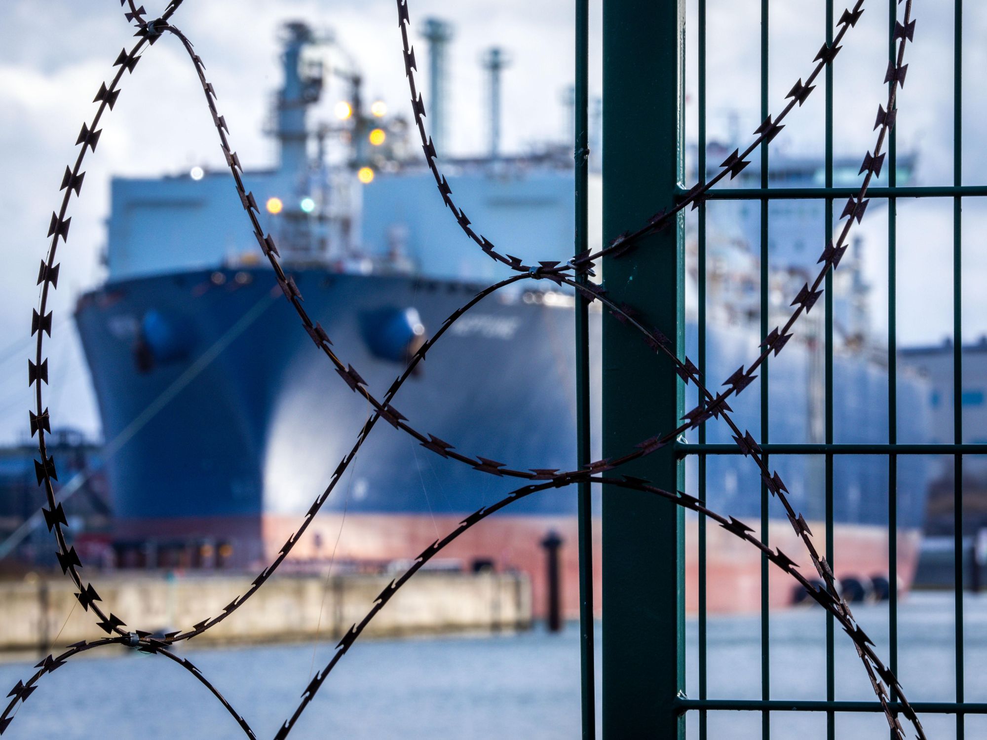 photo of a tanker ship behind barbed wire