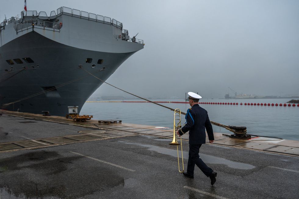 photo of a trombone player from the navy and a ship