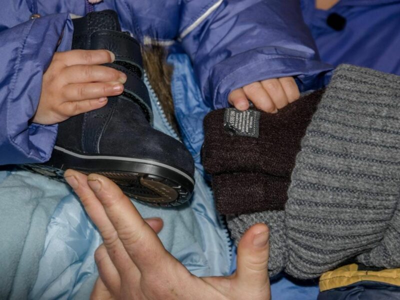 Photo of a Ukrainian child holding a winter boot and a wooly hat