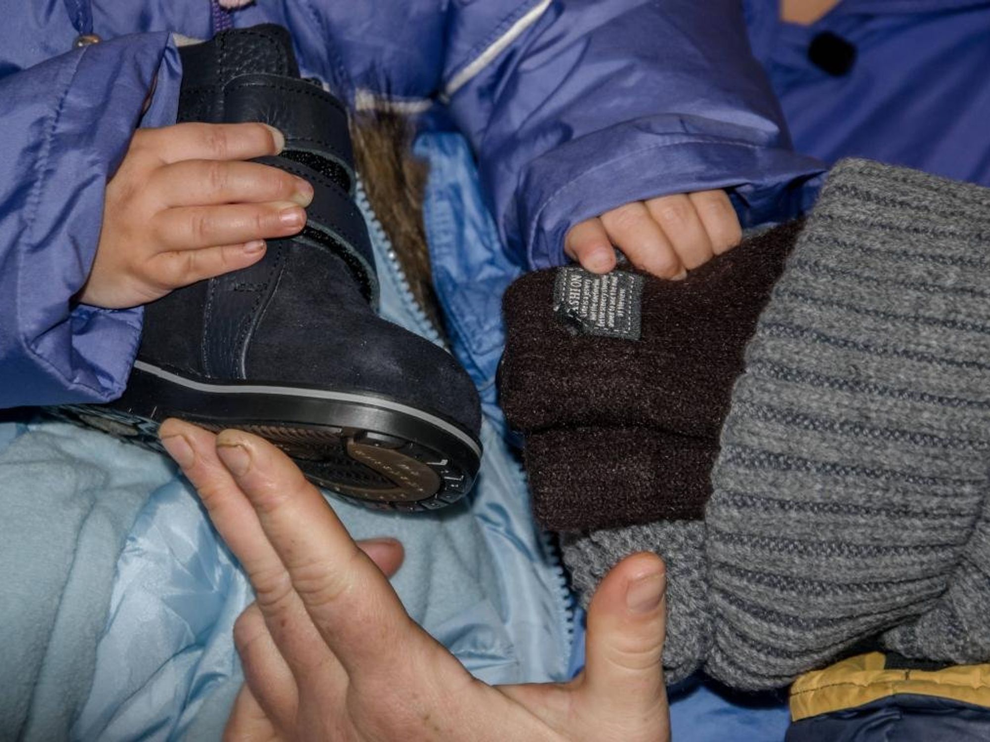 Photo of a Ukrainian child holding a winter boot and a wooly hat