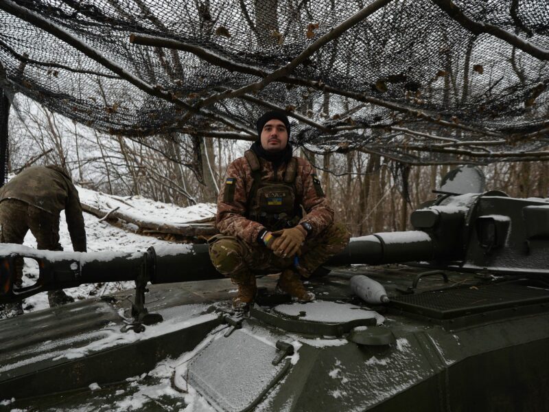 Photo of a Ukrainian soldier crouching on a tank near Kyiv in a snowy landscape