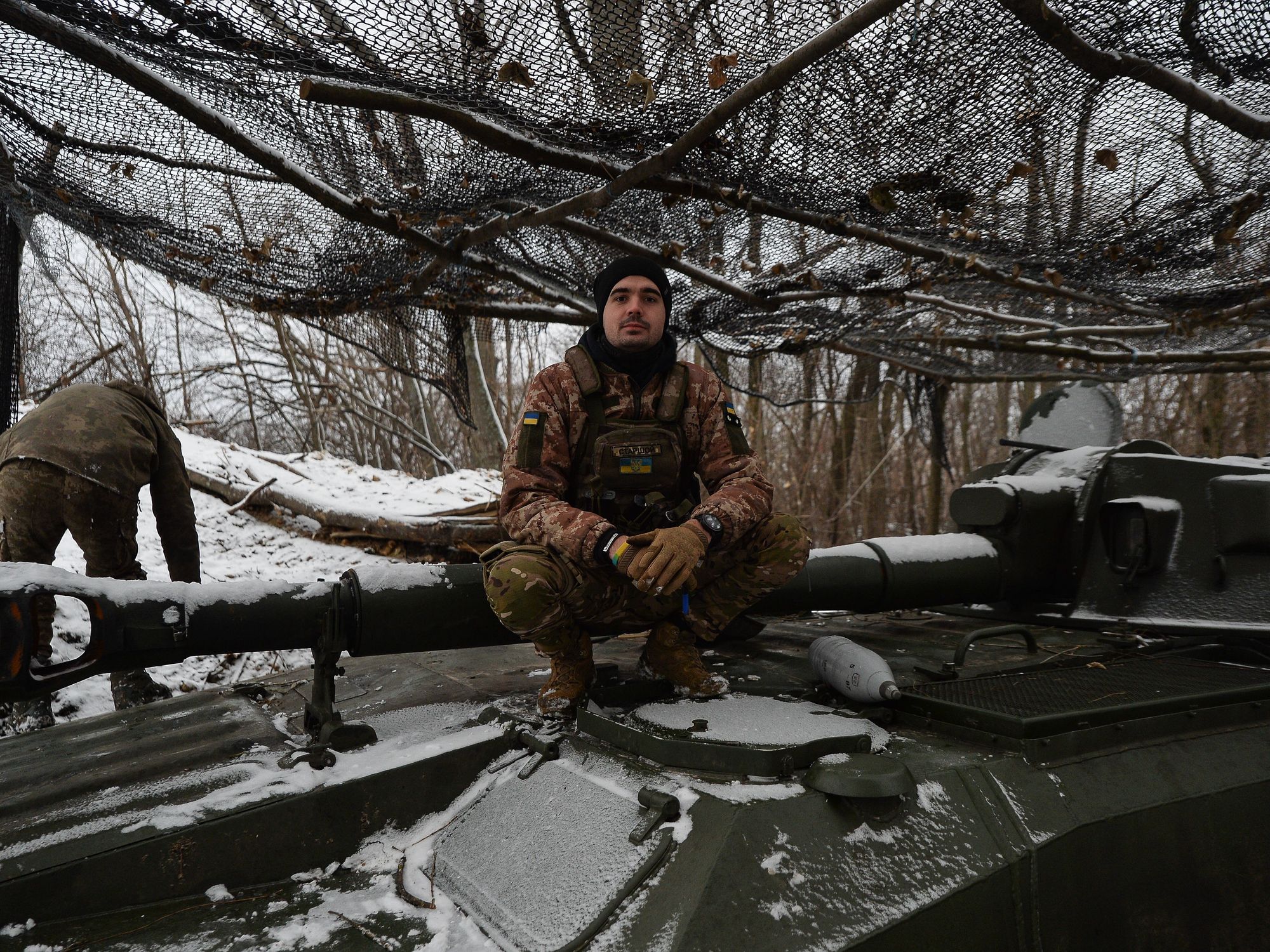 Photo of a Ukrainian soldier crouching on a tank near Kyiv in a snowy landscape