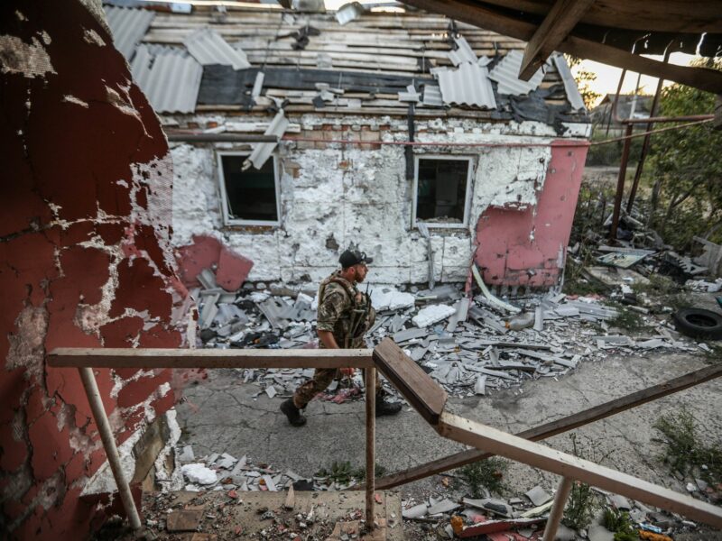 Photo of a Ukrainian soldier walking past a destroyed building