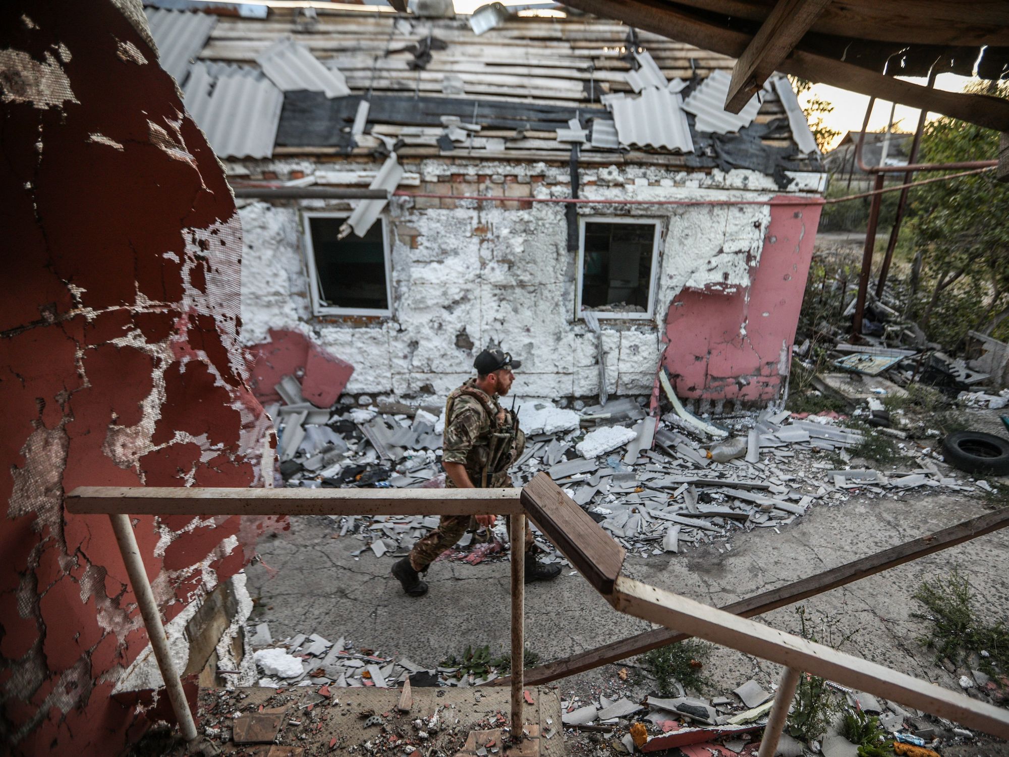 Photo of a Ukrainian soldier walking past a destroyed building