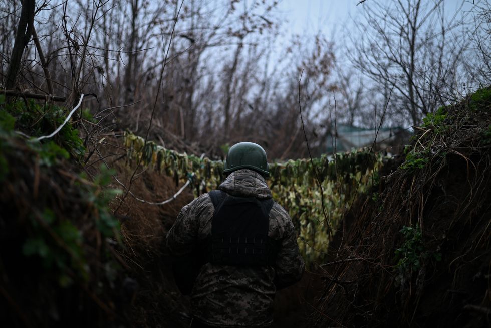 Photo of a Ukranian soldier's back as he walks down a trench.