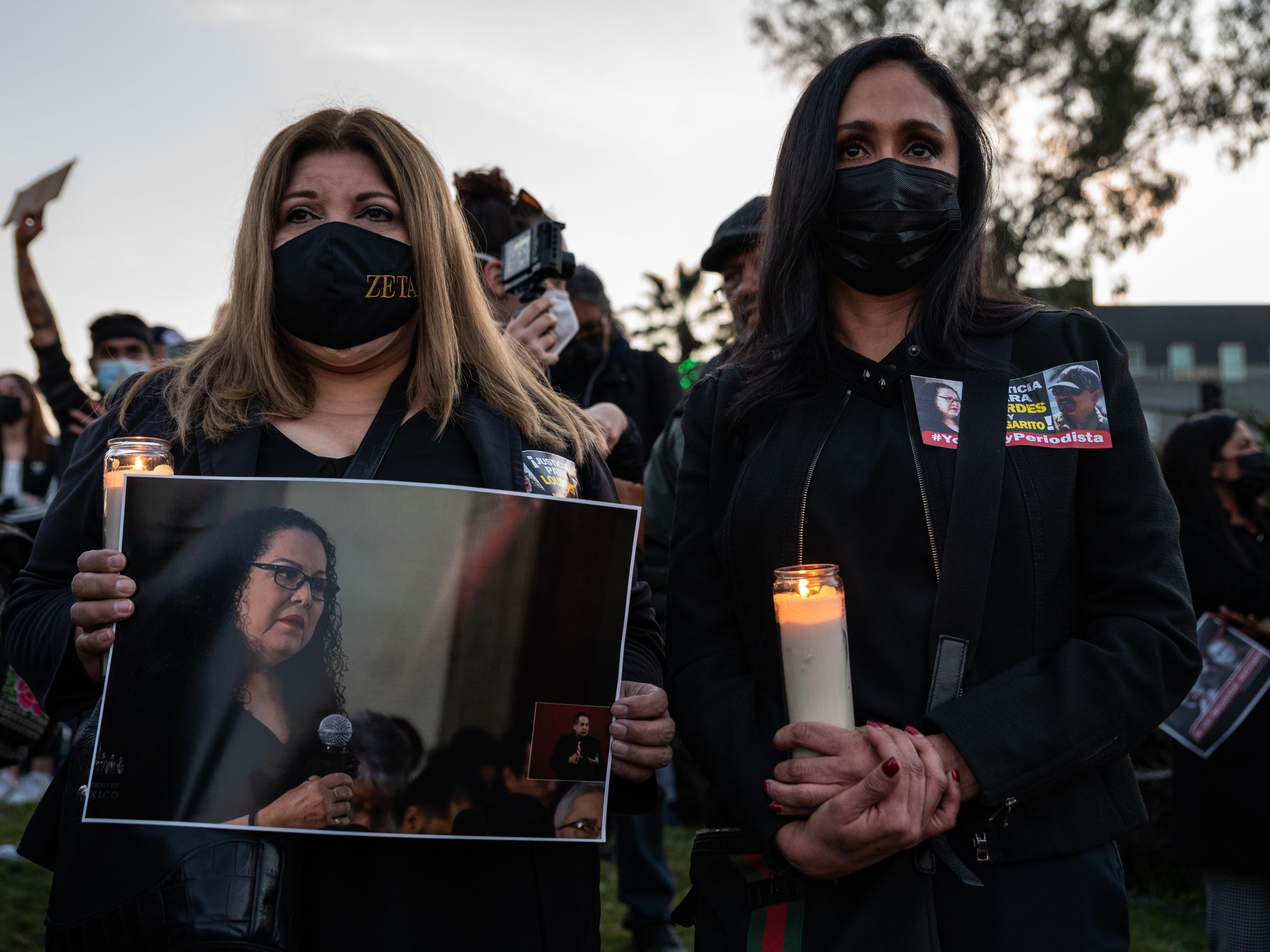 photo of a vigil of two women holding candles and photo of slain journalist Lourdes Maldonado