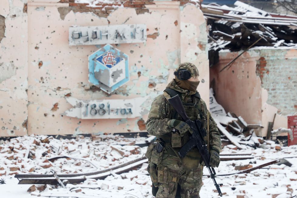 Photo of a Wagner Group fighter in front of a destroyed building in the snow