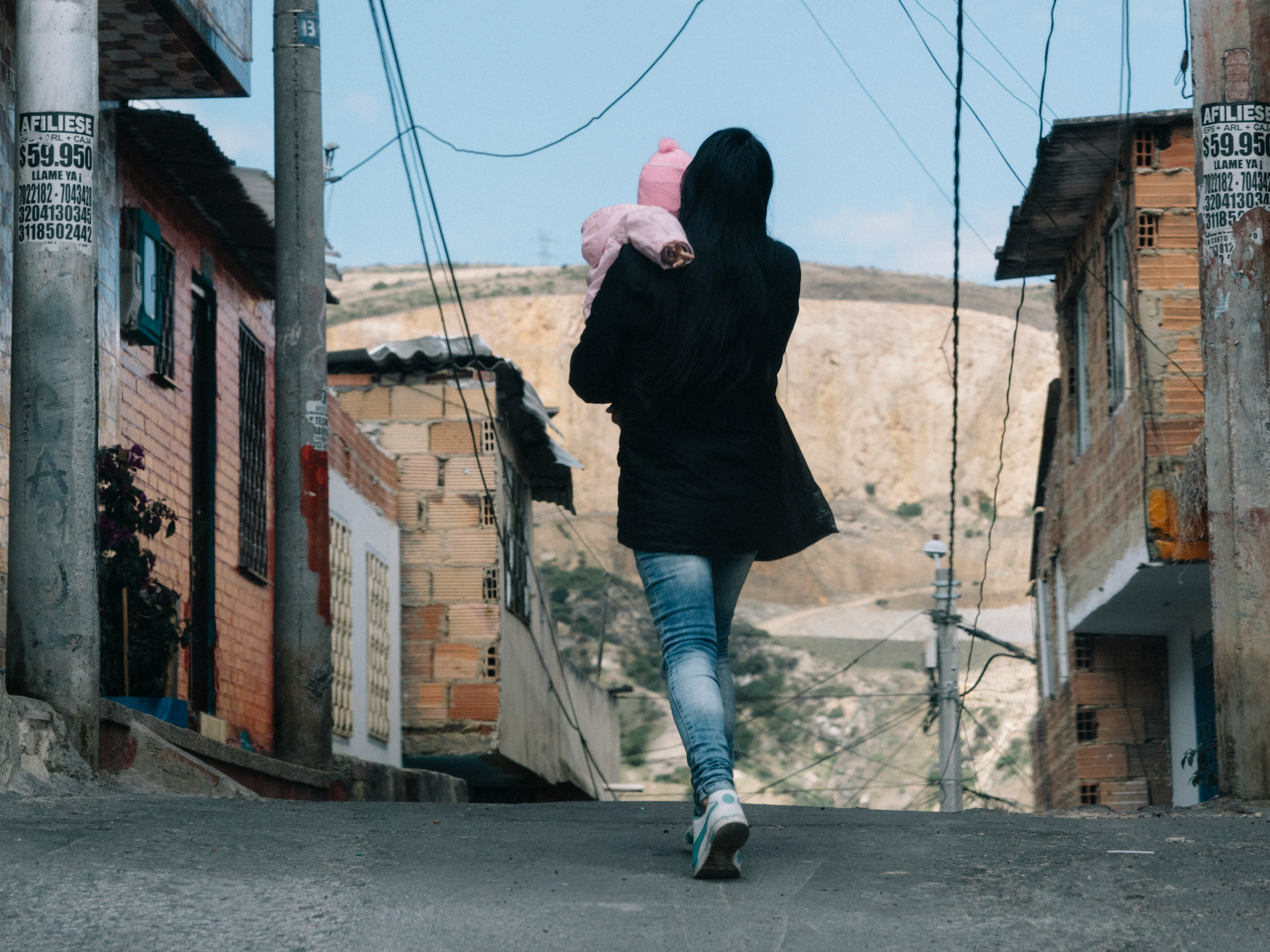 Photo of a woman carrying her child while walking in the streets of Bogota, Colombia
