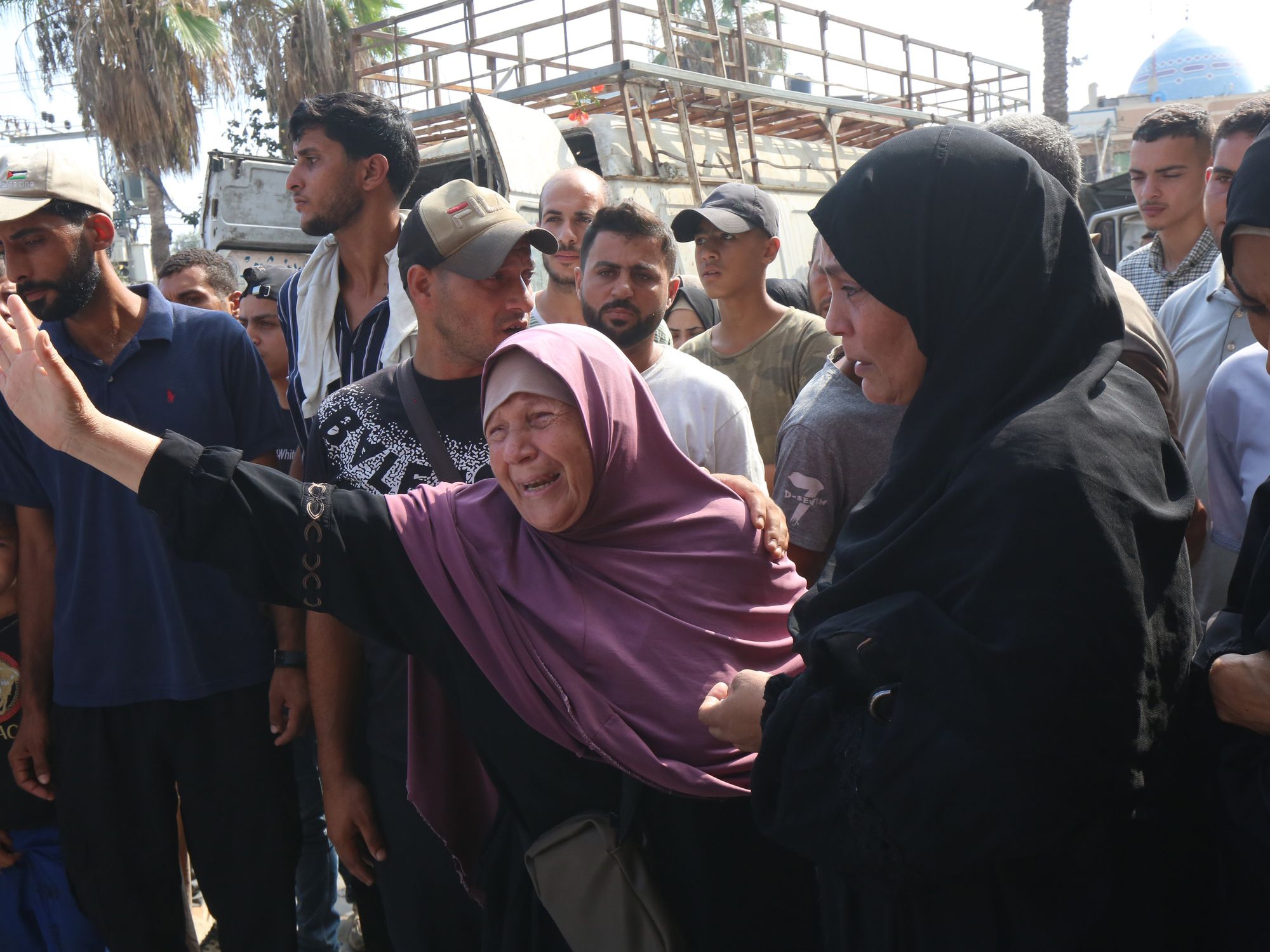 photo of a woman crying and holding up her arm, surrounded by others