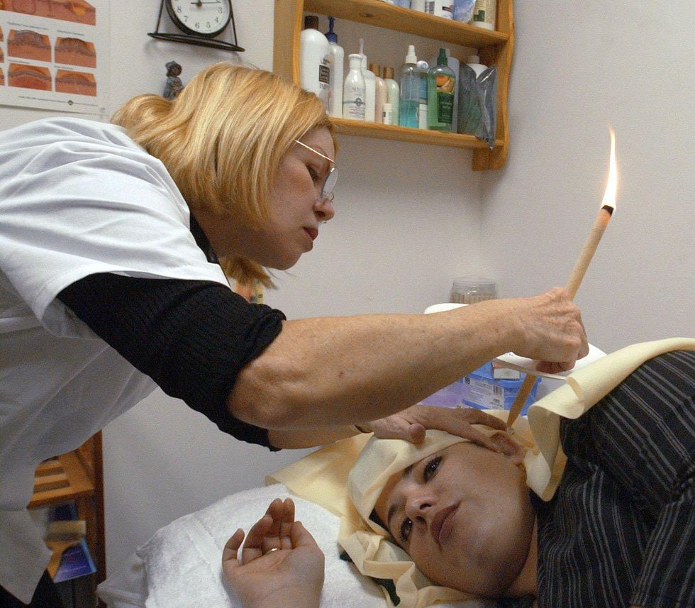 photo of a woman having her ear cleared with burning candle