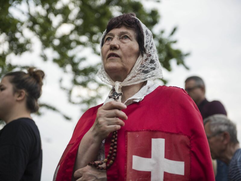 Photo of a woman holding a crucifix with the Polish flag