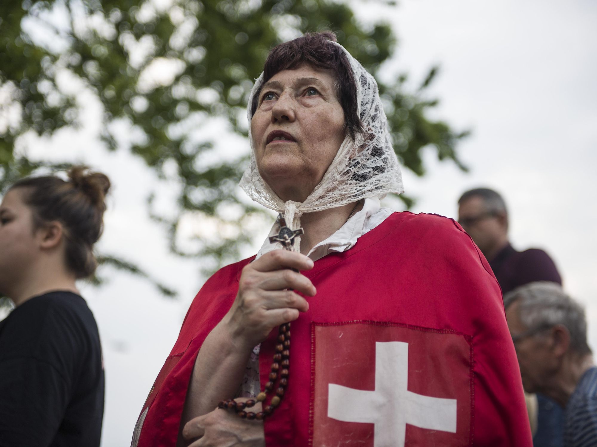 Photo of a woman holding a crucifix with the Polish flag