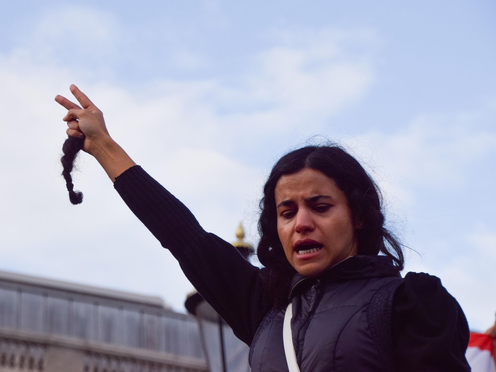 Photo of a woman holding a cut lock of her hair in Mahsa Amini protest​ in London
