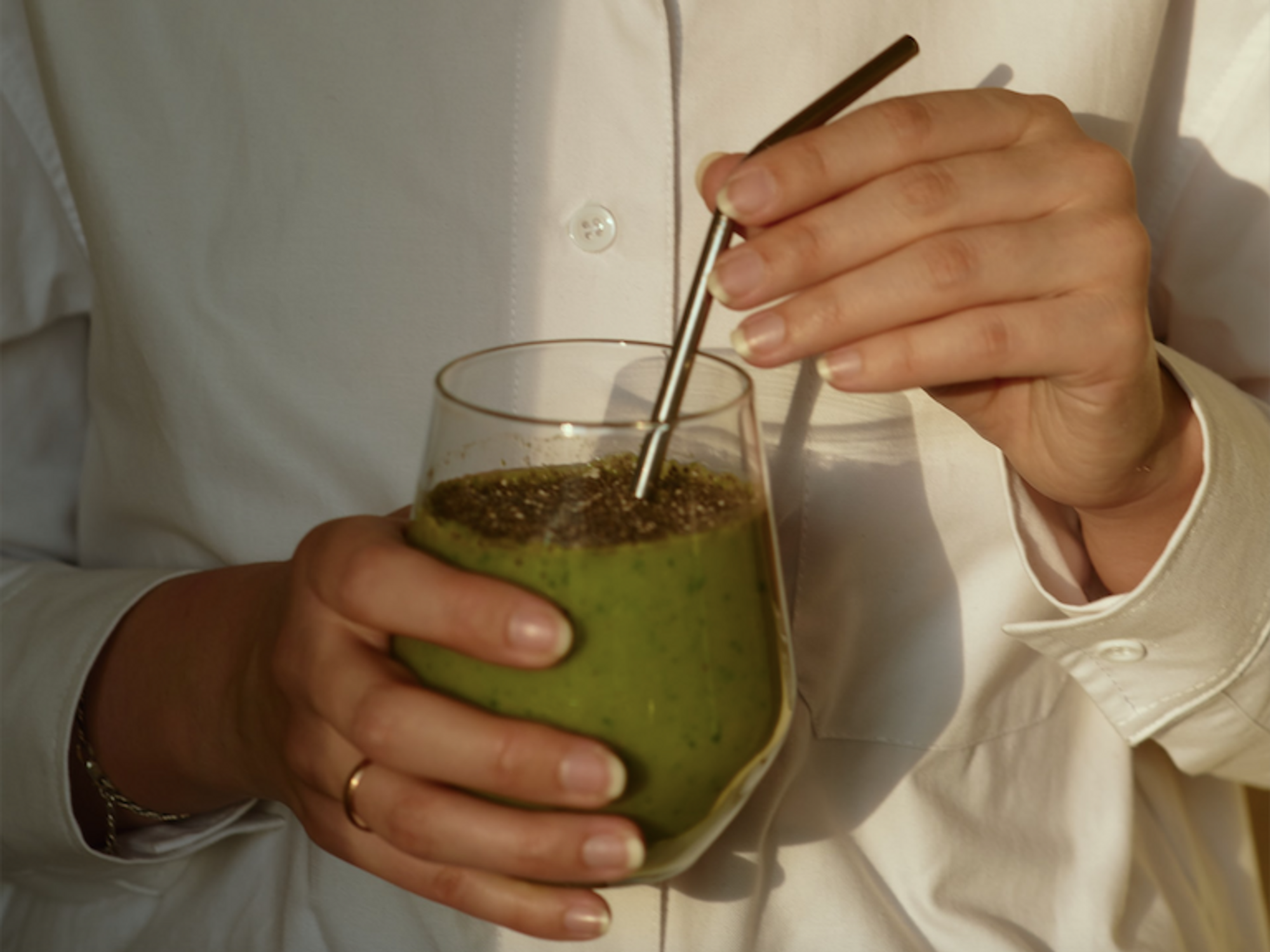 photo of a woman holding a green drink