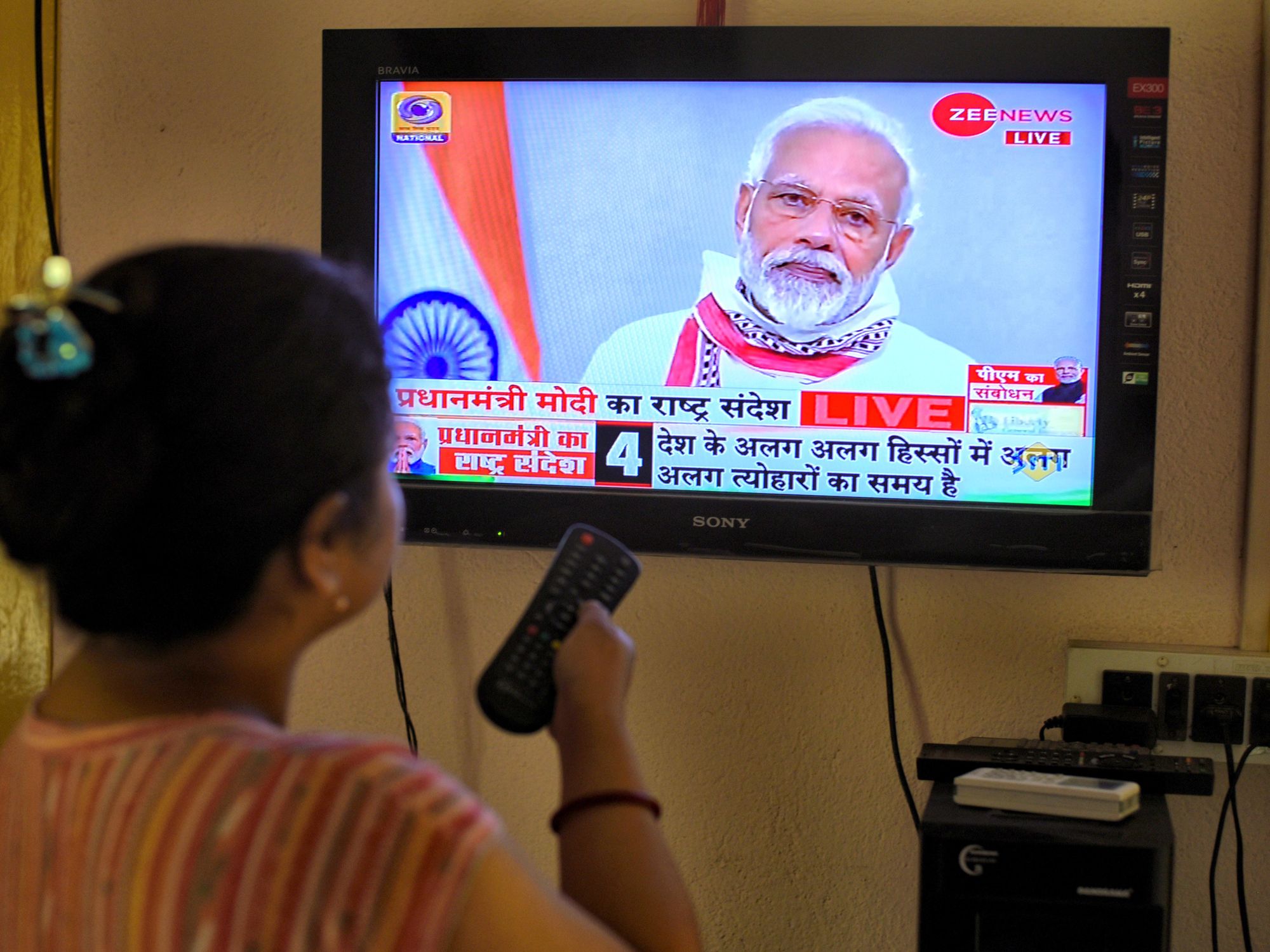 Photo of a woman holding a remote while watching Indian Prime Minister Narendra Modi on TV