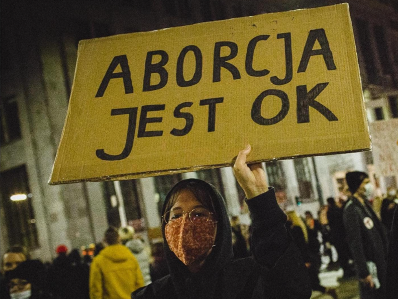 Photo of a woman holding a sign that reads "abortion is ok" ​at a recent pro-abortion rights demonstration in Poland
