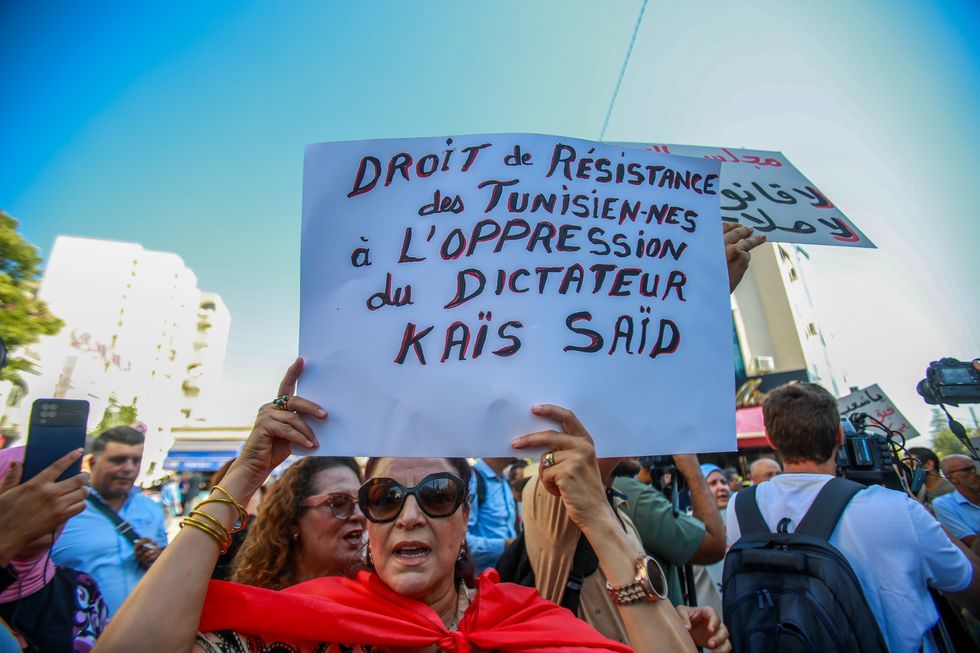 Photo of a woman holding up a sign in protest against the Tunisian president Kais Sayed.