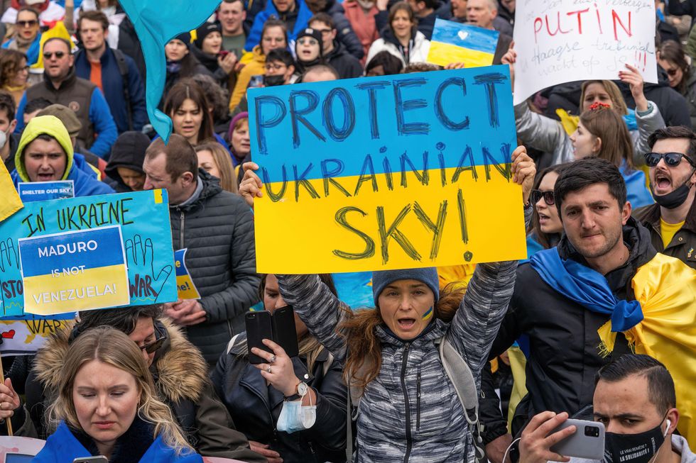 photo of a woman holding up a sign that says "Protect Ukrainian Sky"