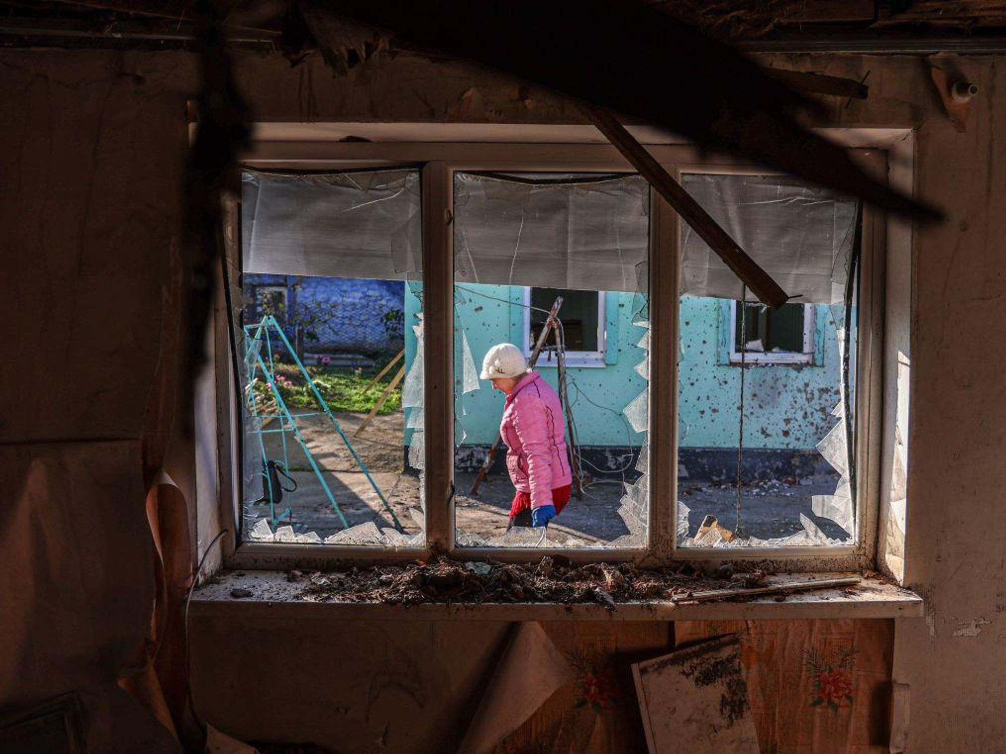 photo of a woman in a pink jacket walking as seen through a blown out window