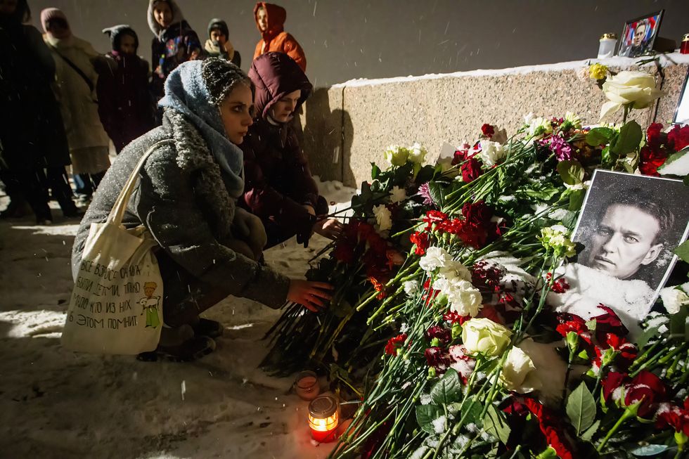 Photo of a woman in Saint Petersburg kneeling next to a memorial dedicated to Alexei Navalny