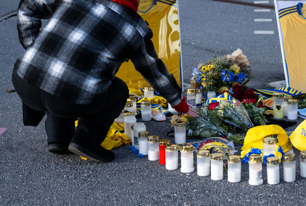 Photo of a woman kneeling down to lay flowers at a memorial in Brussels, after an attacker killed two Swedes on Oct. 17