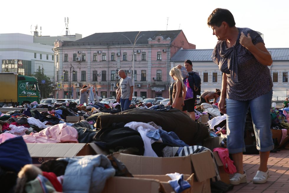 Photo of a woman looking at boxes full of clothes as humanitarian aid is being distributed in Kursk on Aug. 21