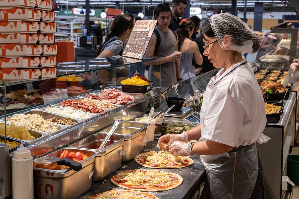 Photo of a woman preparing pizzas at a supermarket in Ukraine