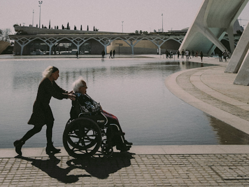 photo of a woman pushing someone in a wheelchair