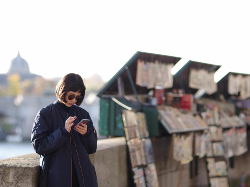 Photo of a woman reading on her smartphone along the banks of the Seine in Paris