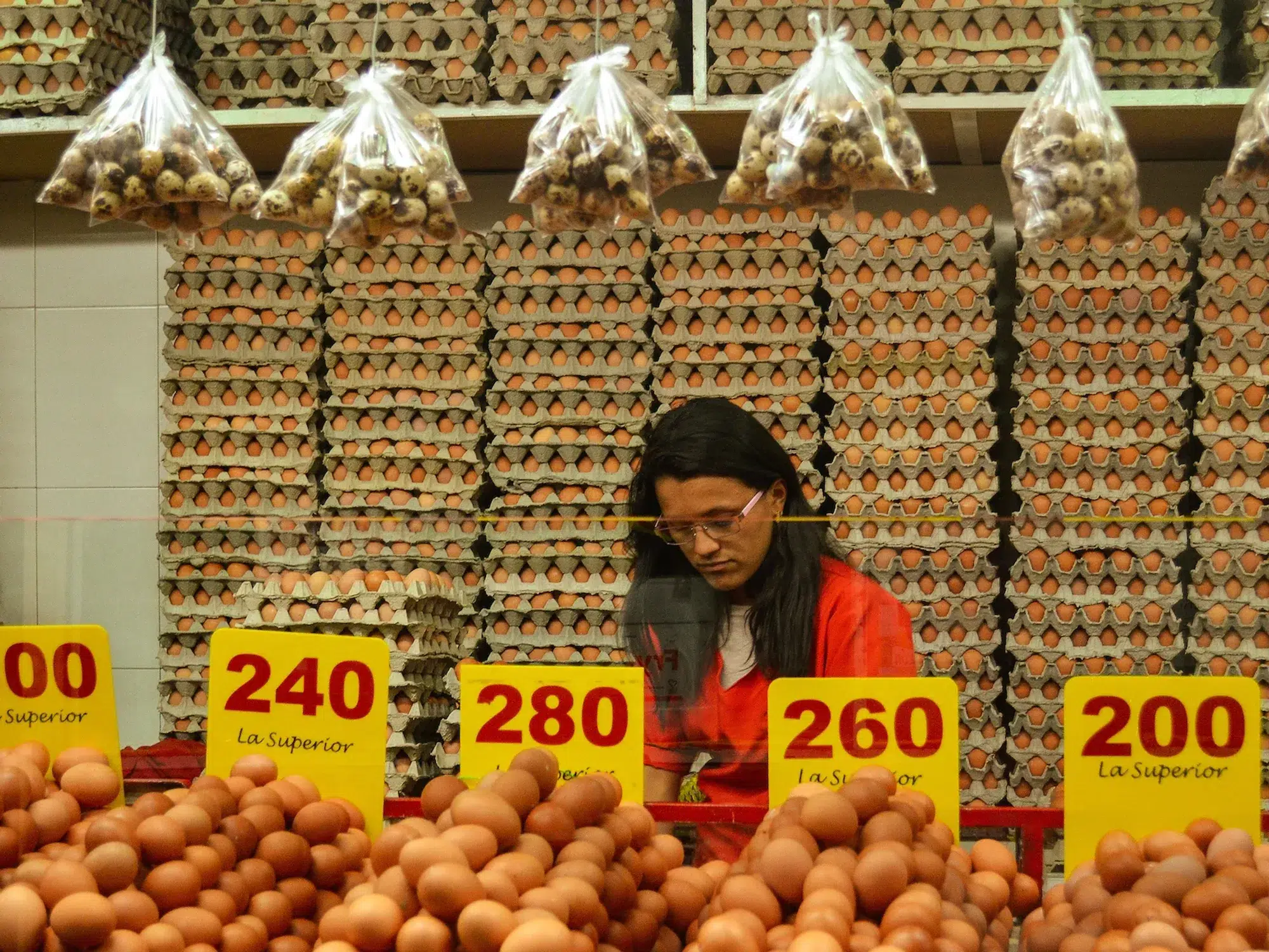 Photo of a woman shopping for eggs, surrounded by the product sold at different sizes.
