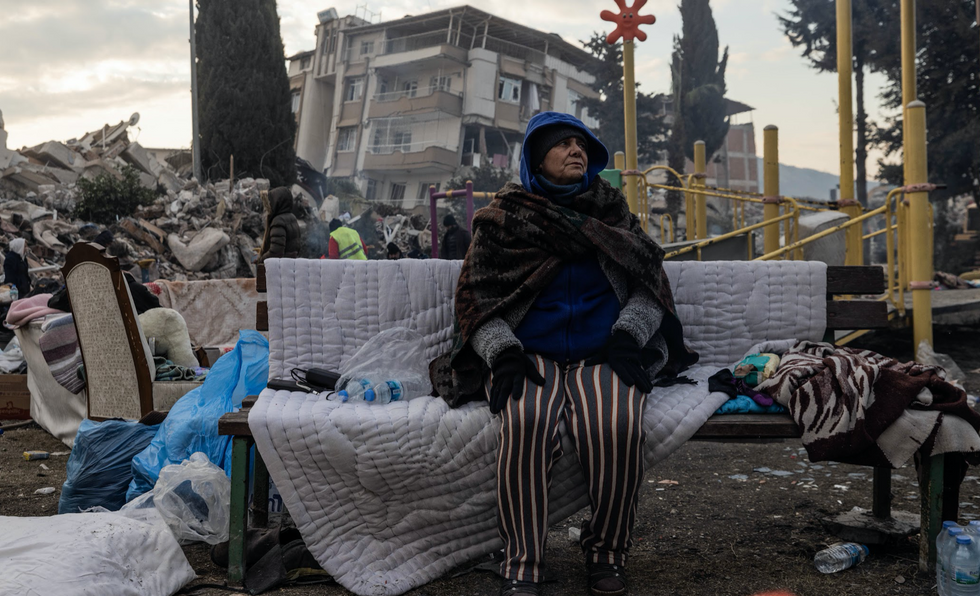 photo of a woman sitting in the rubble in Turkey after the earthquake