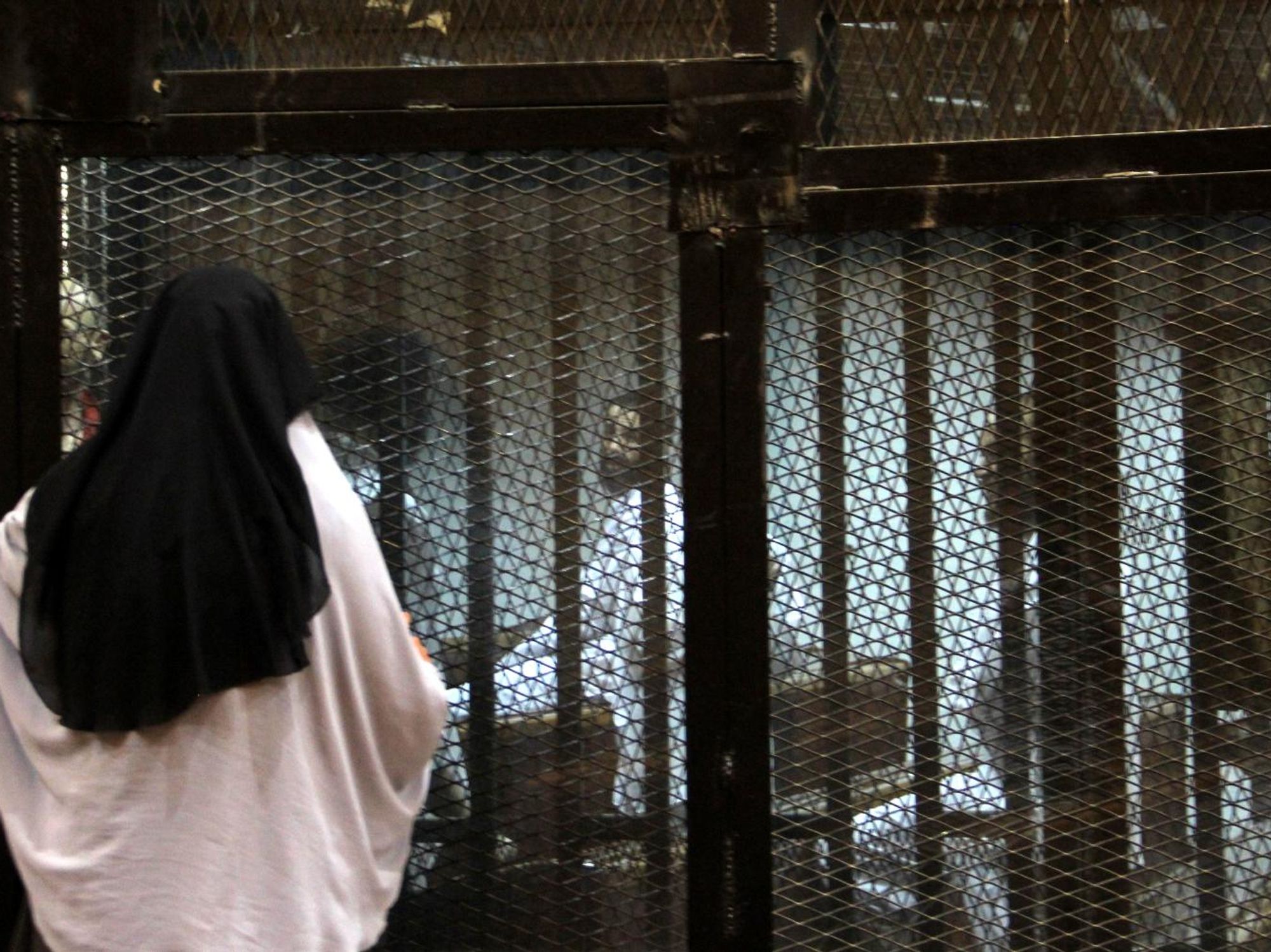 photo of a woman speaking with imprisoned defendants during a trial in a Cairo court