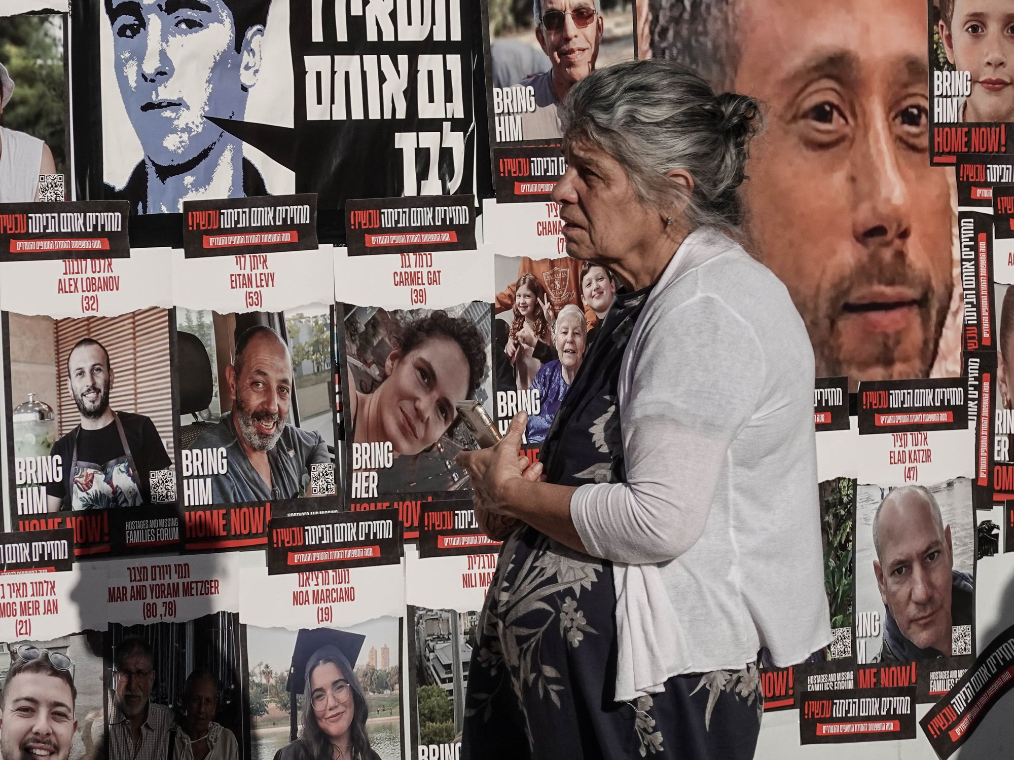Photo of a woman standing in front of a wall dedicated to the hostages taken by Hamas