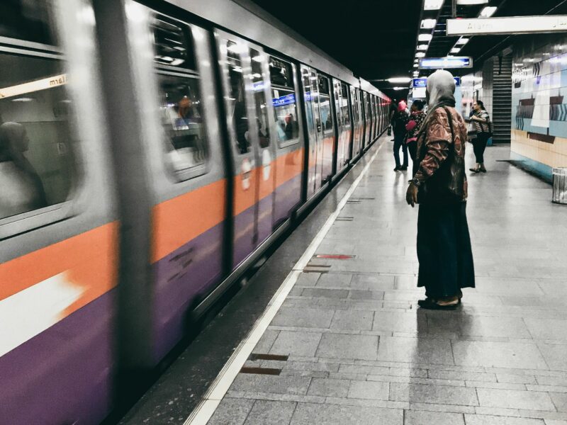 Photo of a woman standing on a platform as a metro arrives
