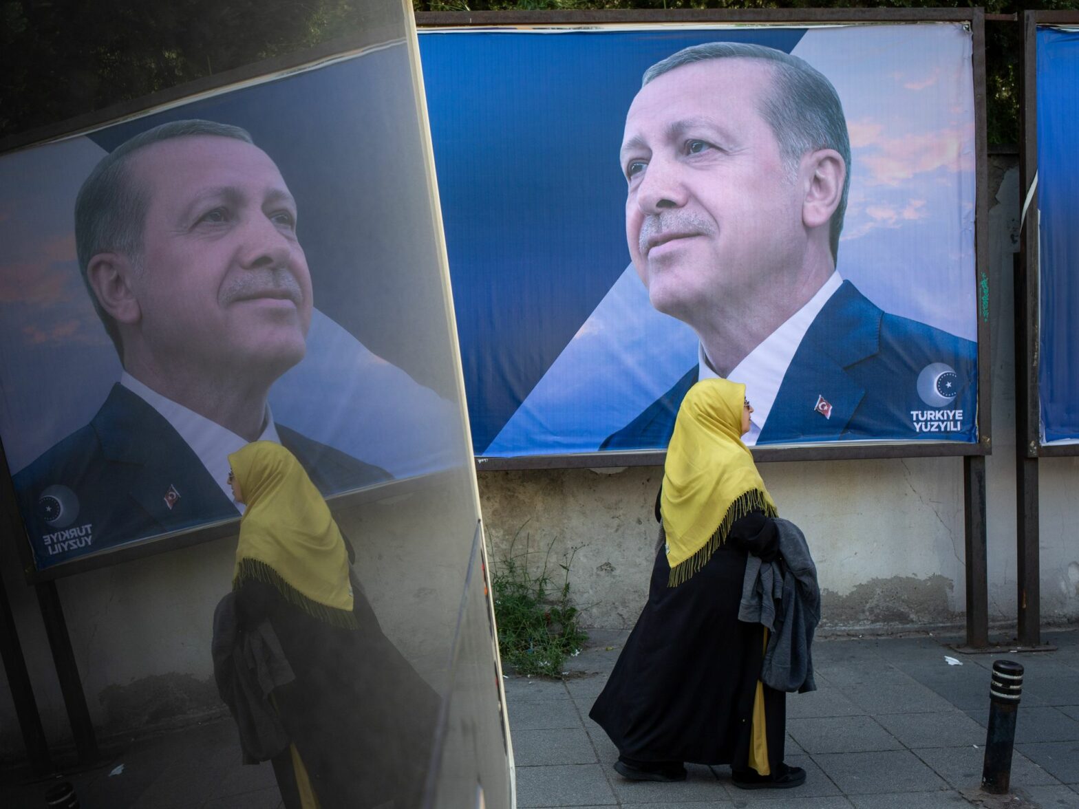 Photo of a woman walking by a campaign poster of Turkish President and People's Alliance's presidential candidate Recep Tayyip Erdogan in Istanbul