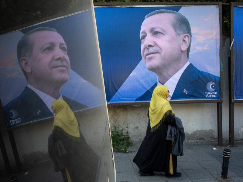 Photo of a woman walking by a campaign poster of Turkish President and People's Alliance's presidential candidate Recep Tayyip Erdogan in Istanbul