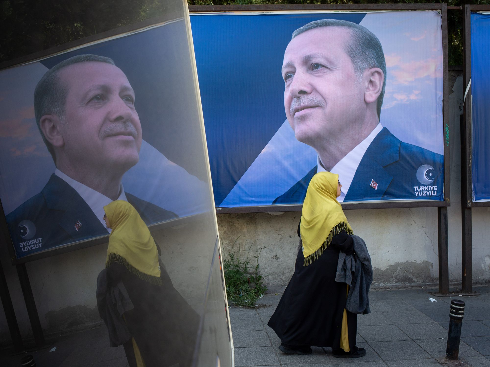 Photo of a woman walking by a campaign poster of Turkish President and People's Alliance's presidential candidate Recep Tayyip Erdogan in Istanbul
