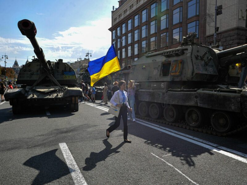 Photo of a woman walking in Kyiv next to a disused Russian tank