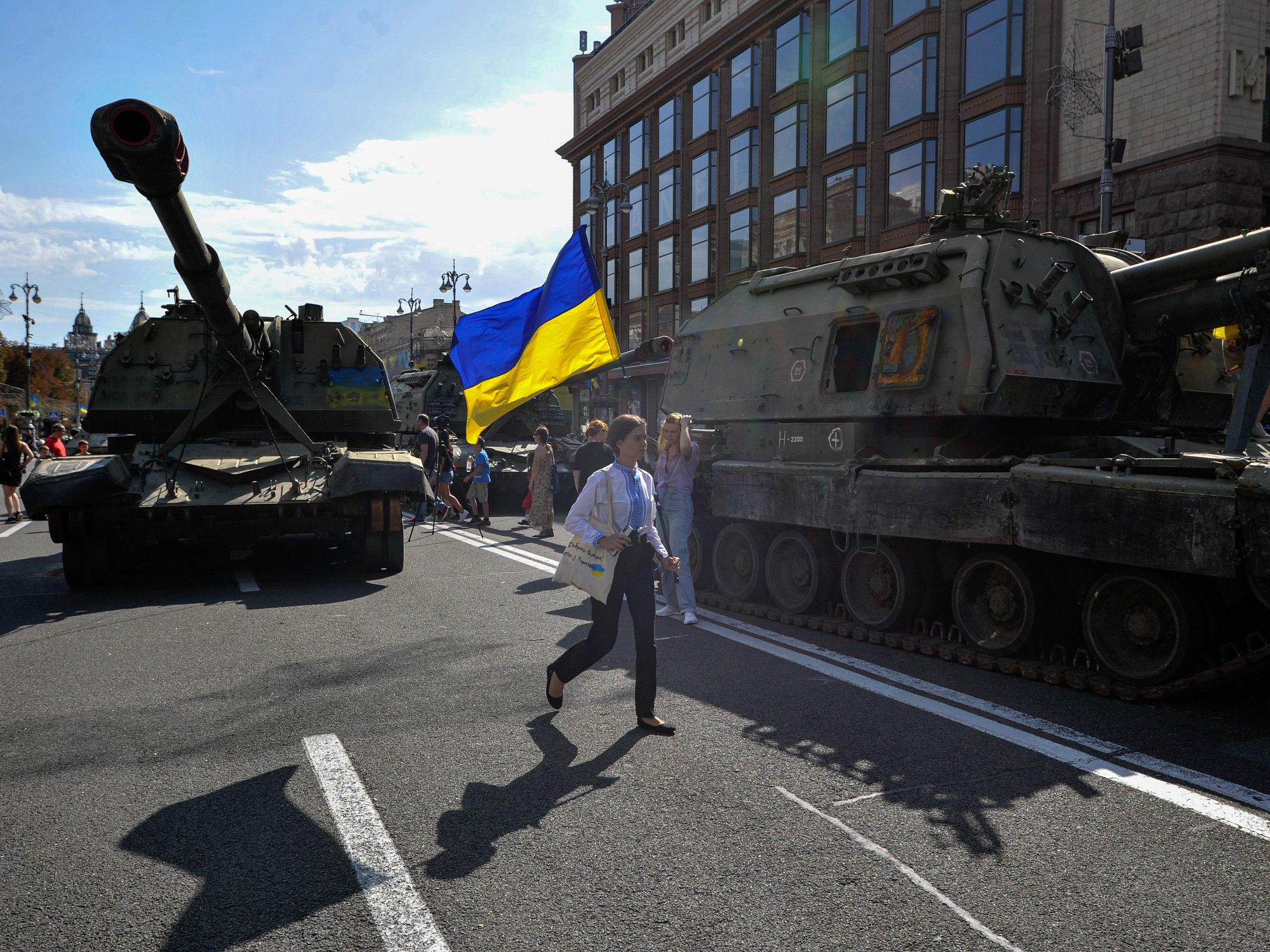 Photo of a woman walking in Kyiv next to a disused Russian tank