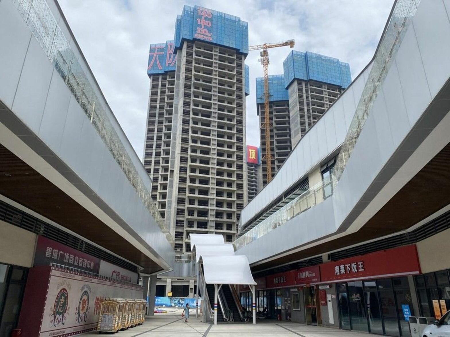 Photo of a woman walking near tall empty skyscrapers in Shaoguan.