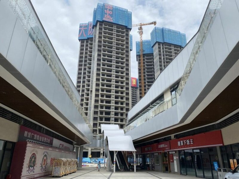 Photo of a woman walking near tall empty skyscrapers in Shaoguan.