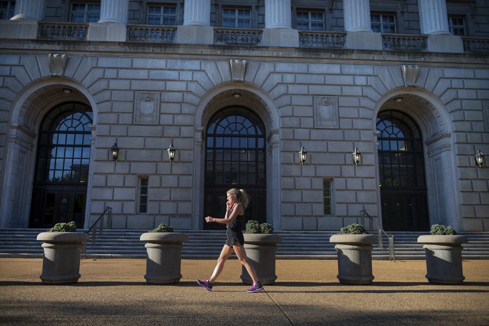 photo of a woman walking past a big government building