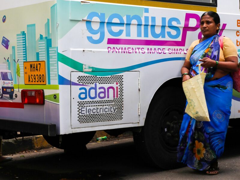 Photo of a woman walking past a mobile van of Adani electricity in Mumbai, India.