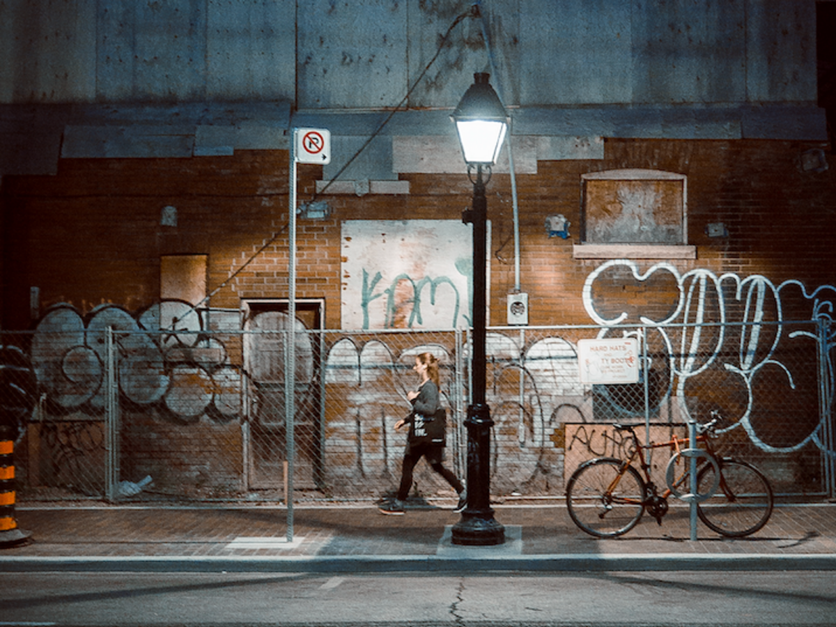 Photo of a woman walking past a street lamp at night