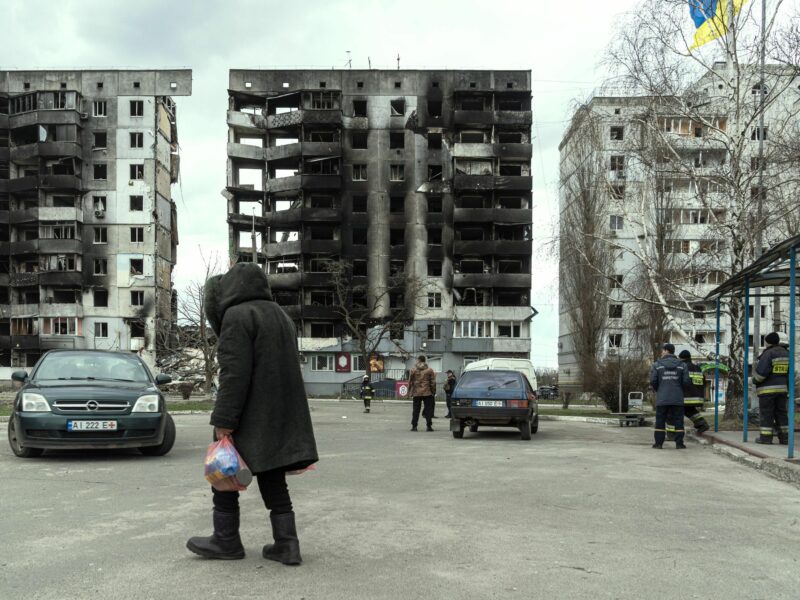 Photo of a woman walking past destroyed buildings in Borodyanka near Kyiv